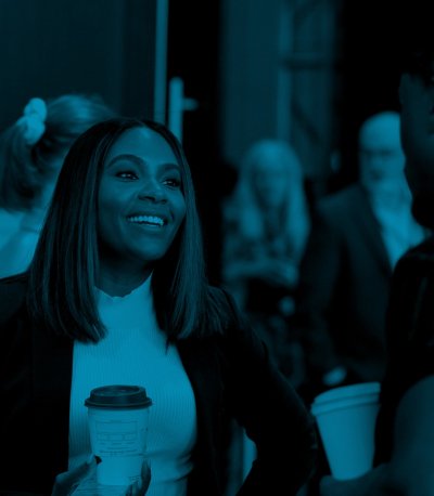 Brittany Collins speaking with another attendee (out of frame) and holding a cup of coffee