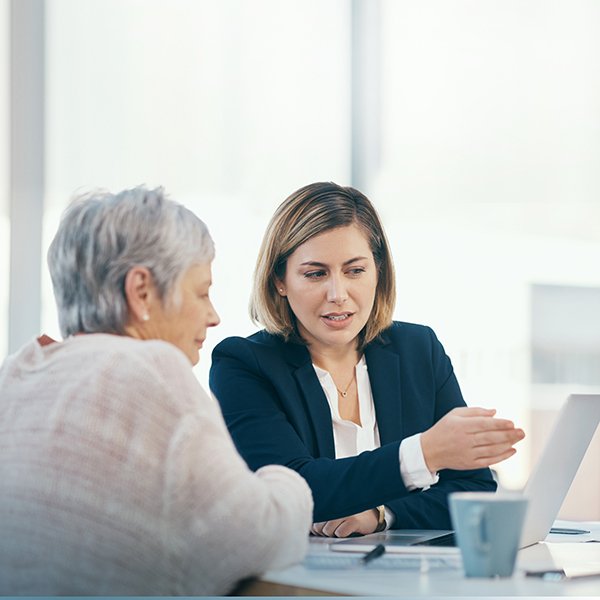 Younger woman pointing to something on your computer and speaking with older female colleague