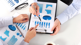 Two people examine a sheet of paper with data graphed on it