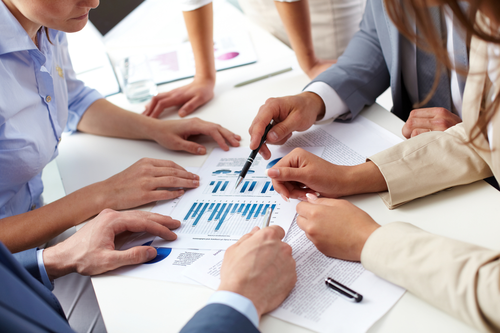 Board meeting where people are analyzing numbers on a sheet