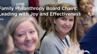 Two white women sit at a table, looking off camera to illustrate the Passages issue brief on Board Chairs