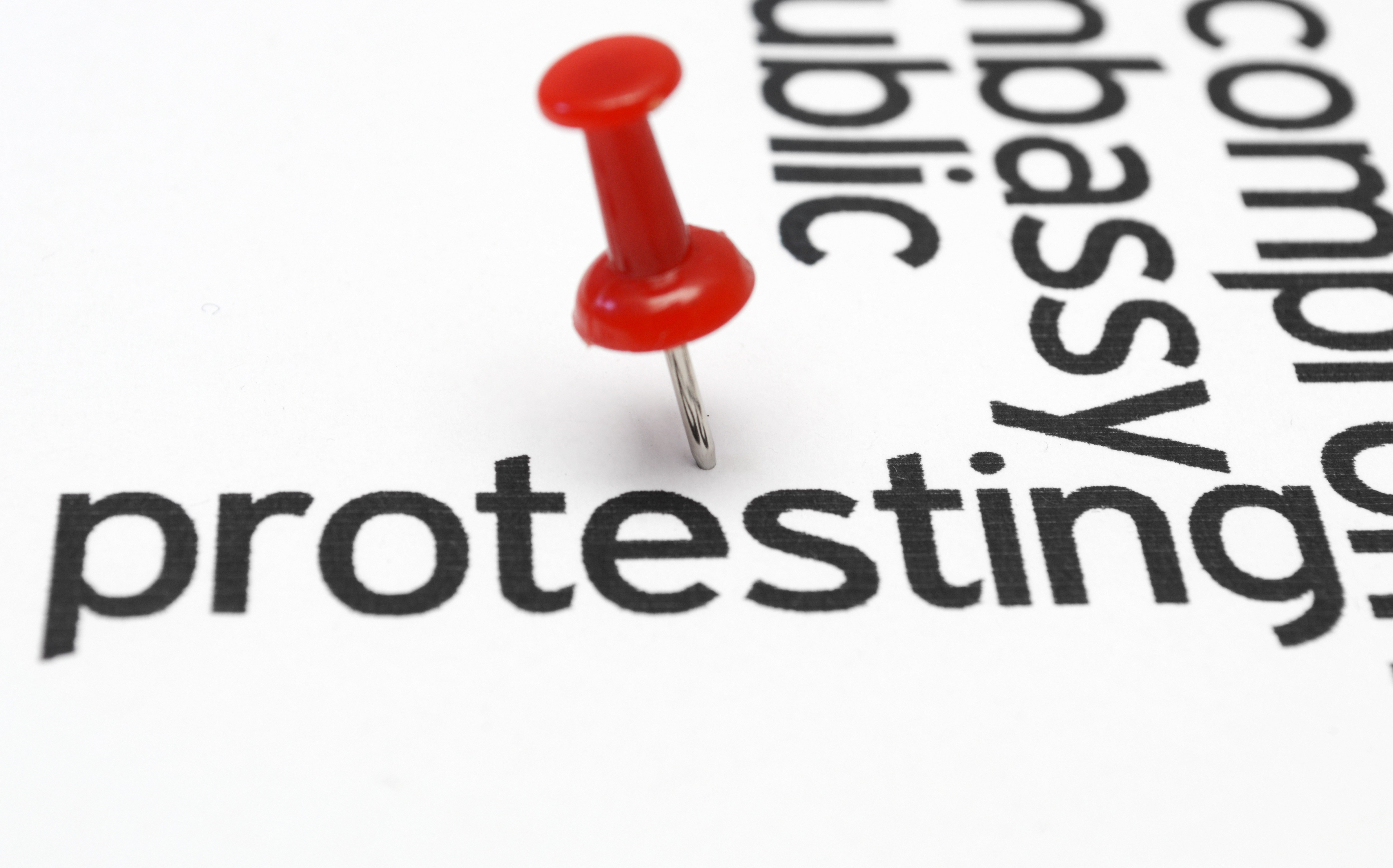 Protesting concept with a tack near the word "protest" on a sheet of paper