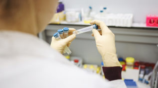 scientist with gloves holding test tube