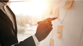 man putting sticky notes on white board