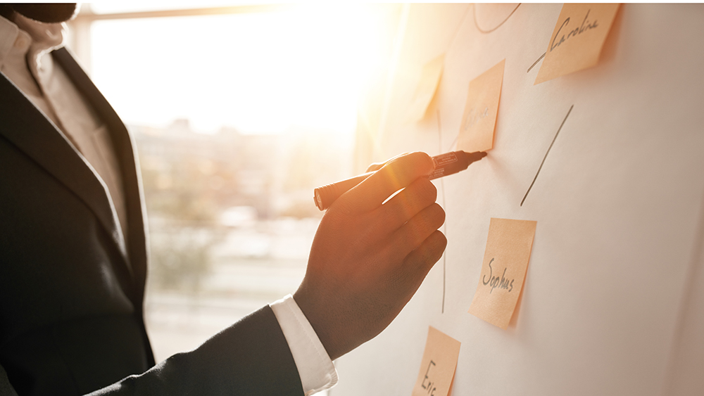 man putting sticky notes on white board