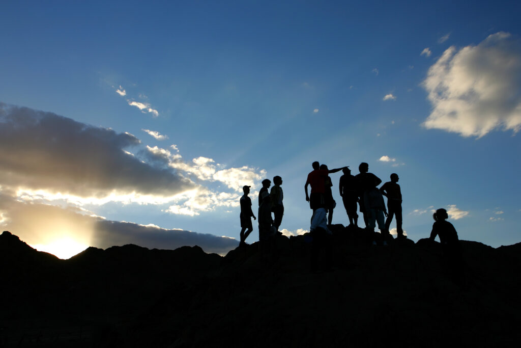 Group of people of on top of the mountain at sunset