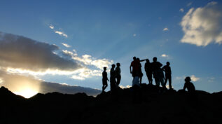 Group of people of on top of the mountain at sunset