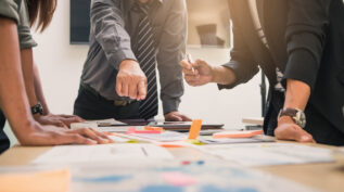 group of people brainstorming around table with papers and sticky notes