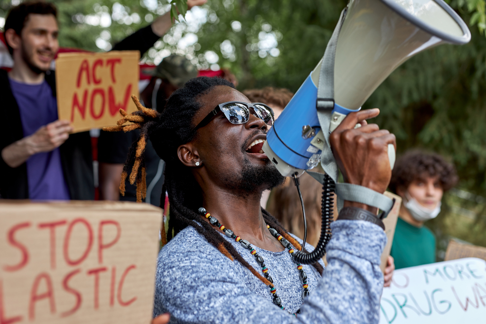 Young black man with megaphone at protest against climate change