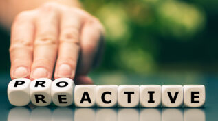 Hand turns dice and changes the word reactive to proactive.