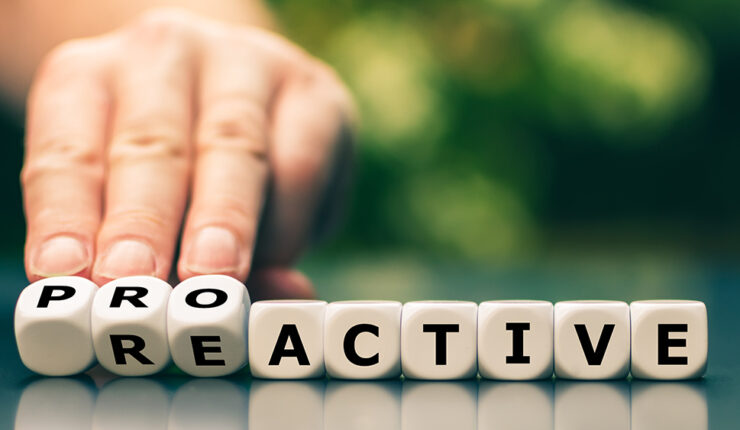 Hand turns dice and changes the word reactive to proactive.