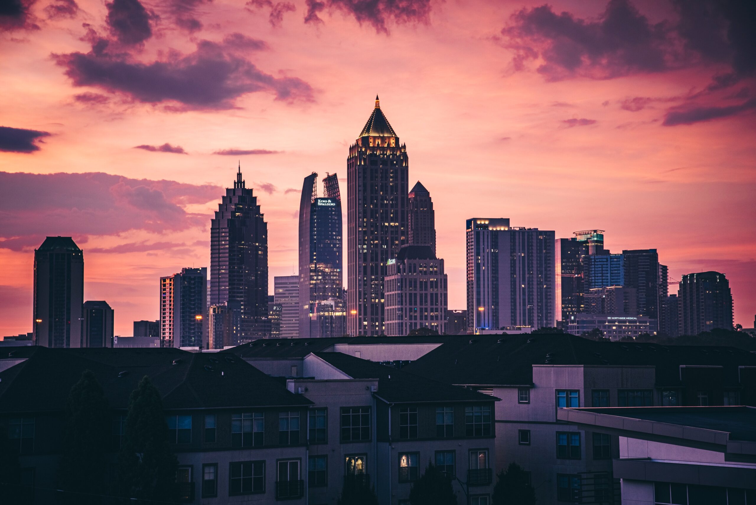 A photo of the city of Atlanta at sunset. Includes high rise buildings and an orange sky. 