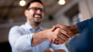 Two people shaking hands across a table