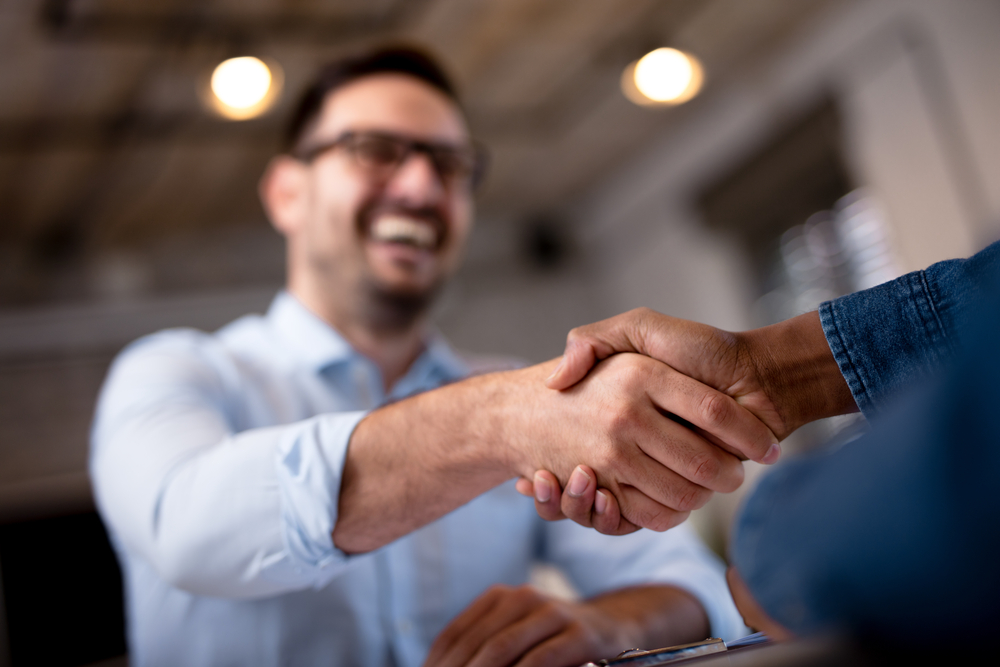 Two people shaking hands across a table