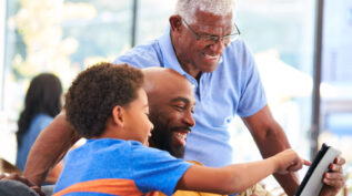 Grandfather, father, and son looking at content on a tablet