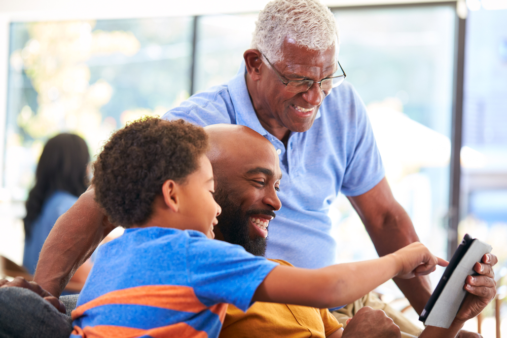 Grandfather, father, and son looking at content on a tablet